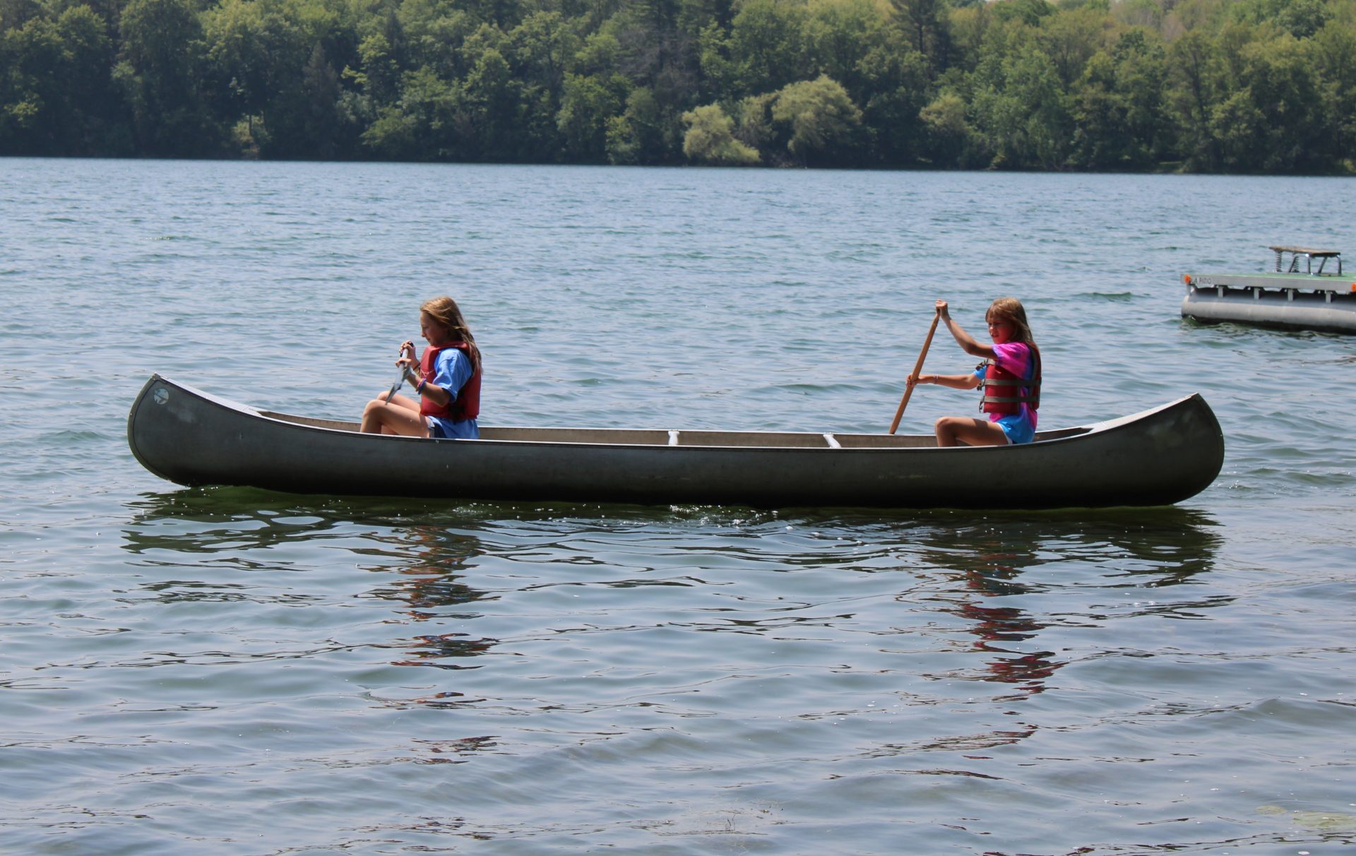  two girls kayaking across a lake 