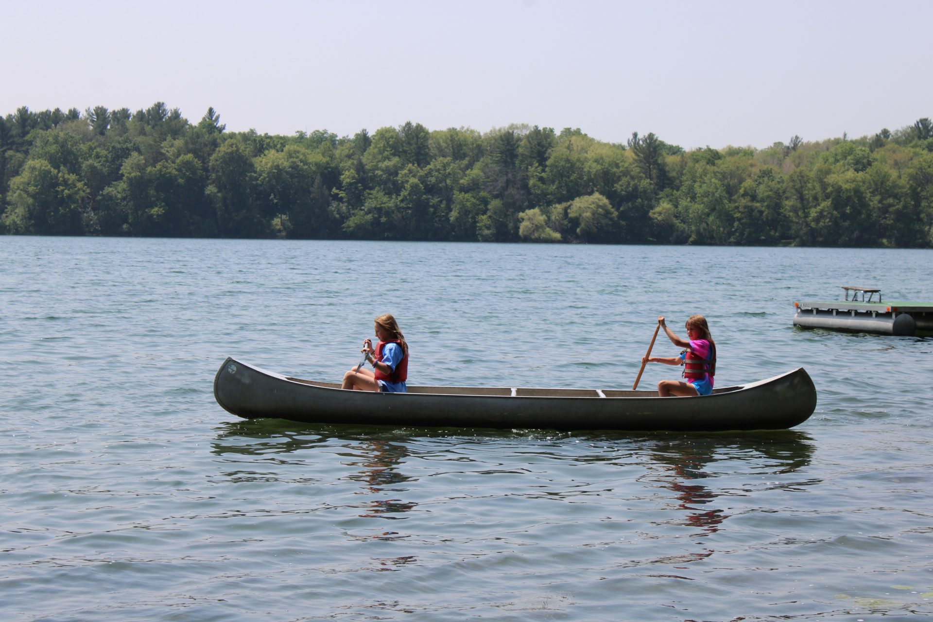  two girls kayaking across a lake 